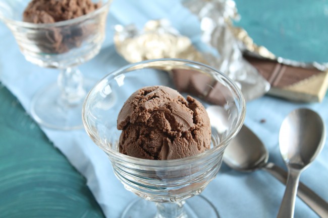Chocolate ice cream in a tall glass serving dish next to a blue napkin.