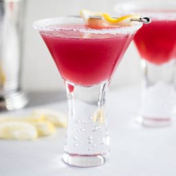 Jolly Pop cocktail in a tall martini glass with a lemon wedge garnish.