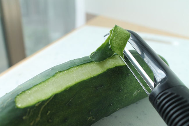 Vegetable peeler peeling a cucumber.