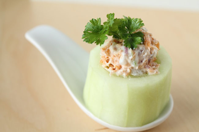 Smoked salmon dip on top of a large piece of cucumber, topped with fresh parsley.