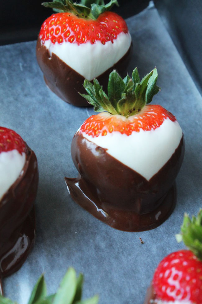 Chocolate covered strawberries on a a baking sheet lined with waxed paper.