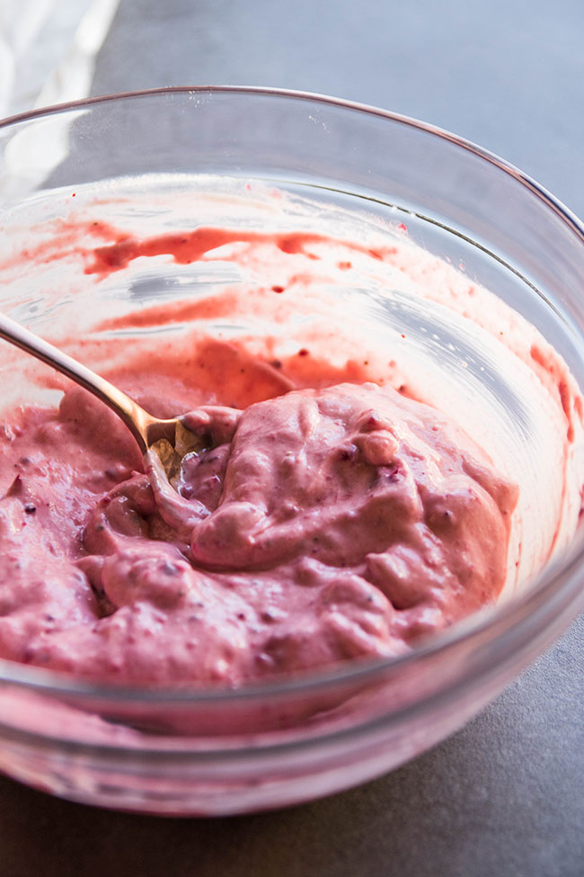 Cranberry mayonnaise sitting in a glass bowl with a gold serving spoon.