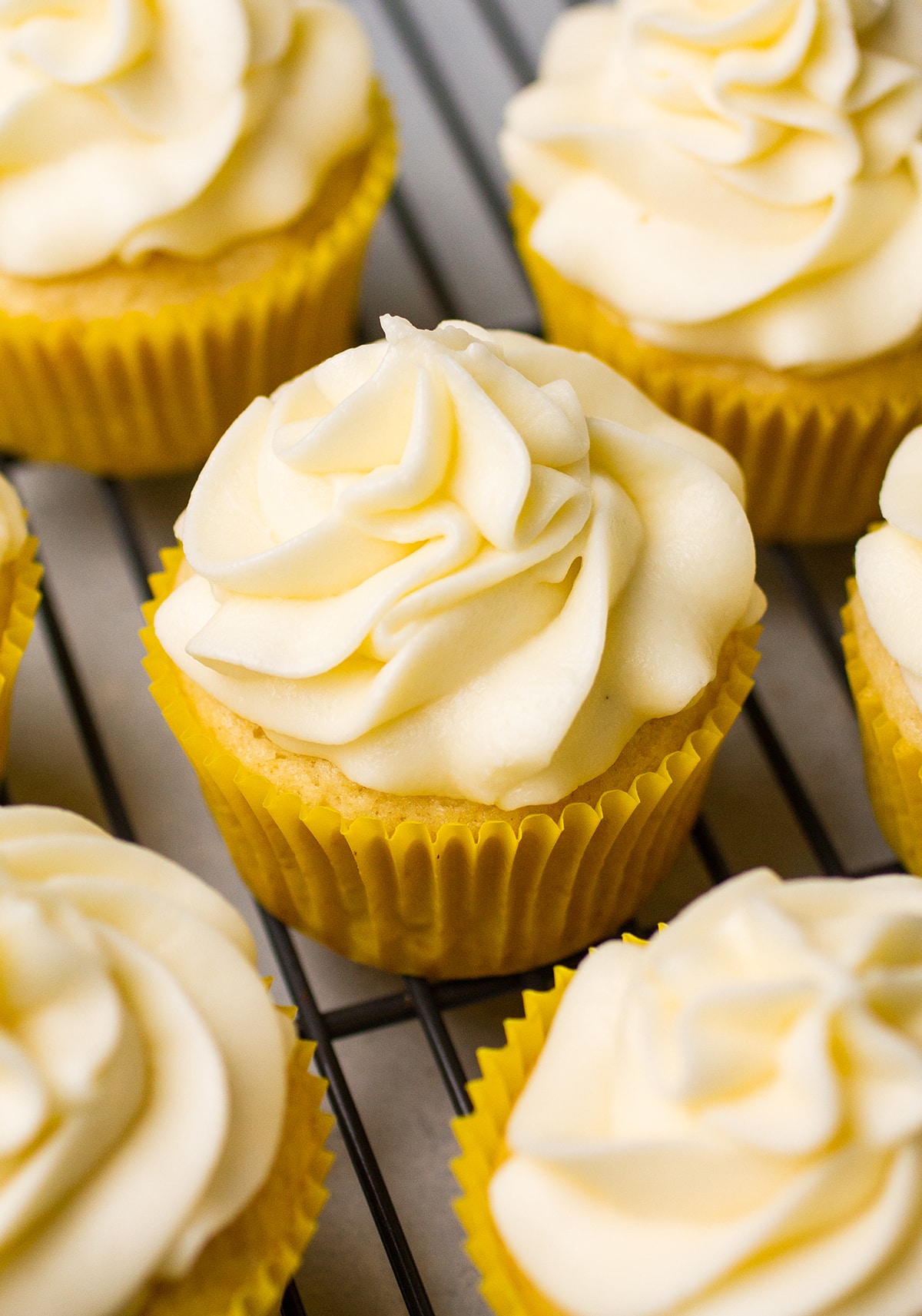 Cupcakes in yellow wrappers, topped with buttercream.