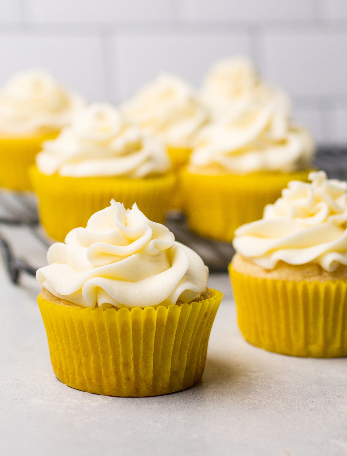 Lemon cupcakes with vanilla buttercream on a white table.