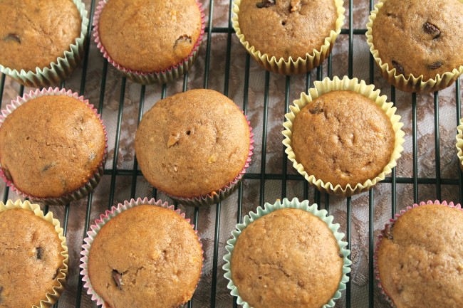 Several banana muffins in various colored wrappers on a wire cooling rack.