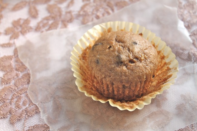 A light yellow cupcake wrapper being peeled off of a banana muffin.