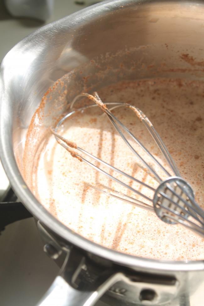 Whisking spices into custard in a small saucepan.