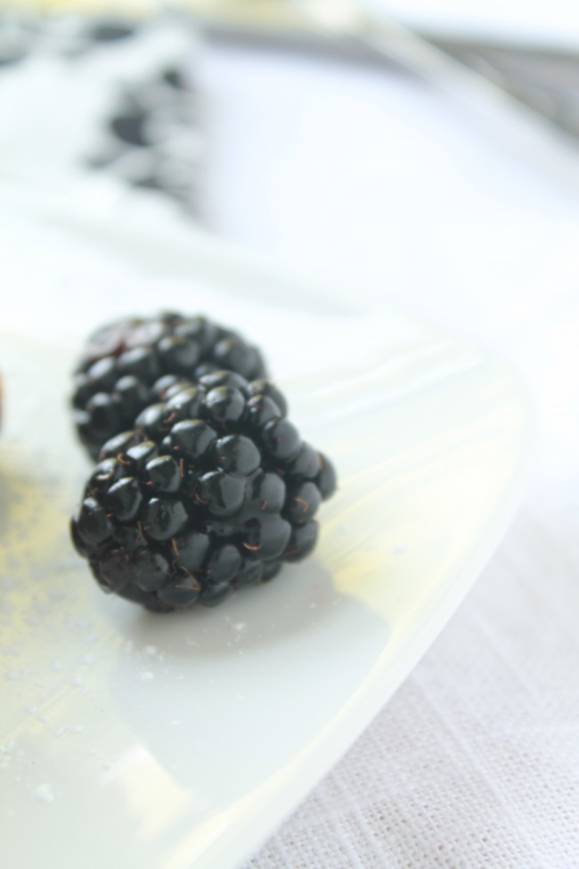 Fresh blackberries on a white plate.