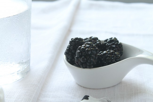 Small white dish filled with fresh blackberries.
