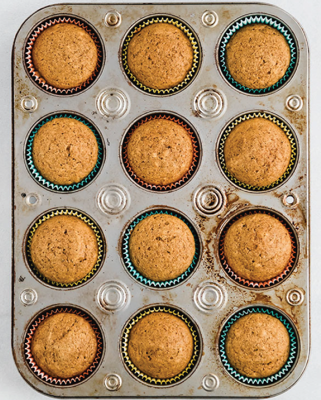 Baked pumpkin cupcakes sitting in a muffin tin.