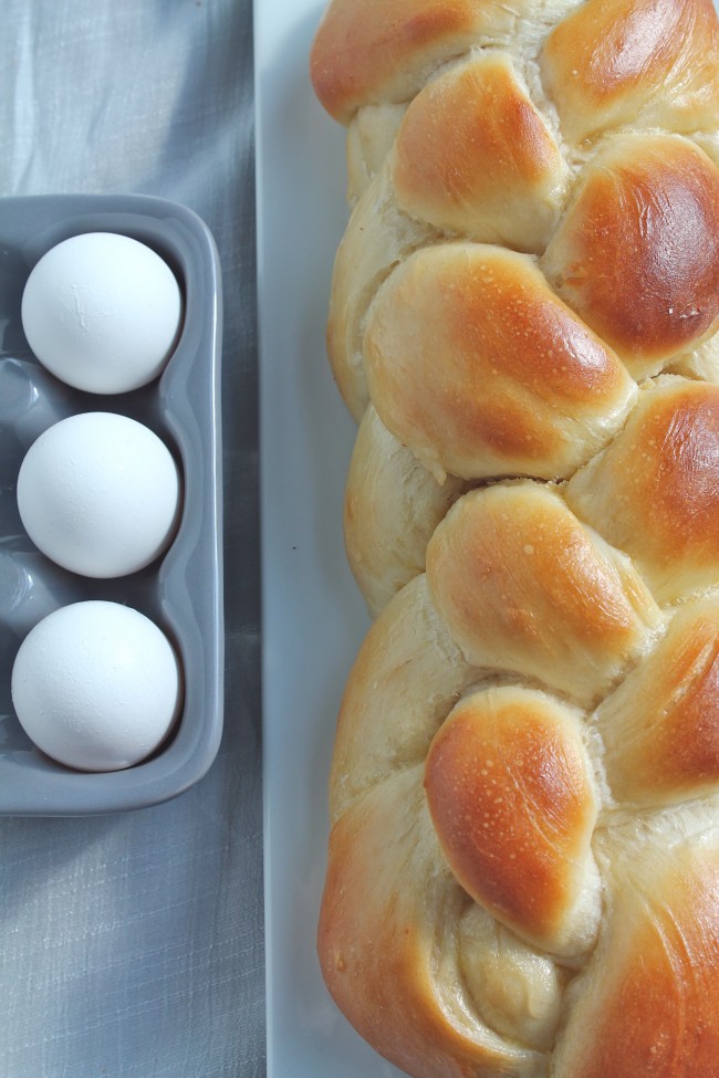 Challah bread loaf next to a small dish of eggs.