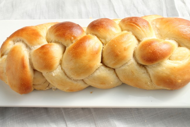 Challah bread loaf on a white serving platter.
