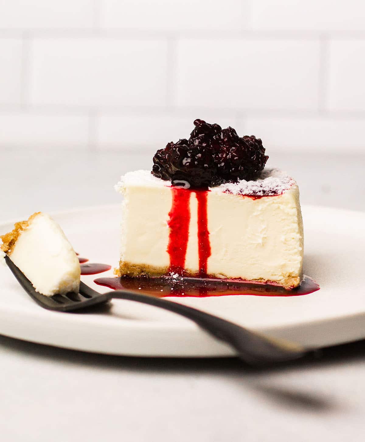 Slice of vanilla cheesecake topped with blackberry sauce.