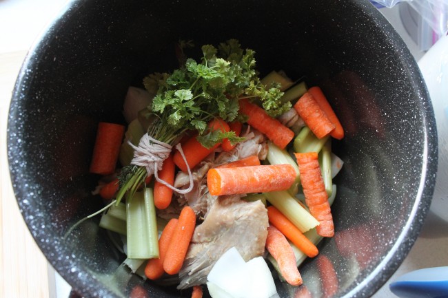 Large black saucepan filled with turkey and vegetables for stock.