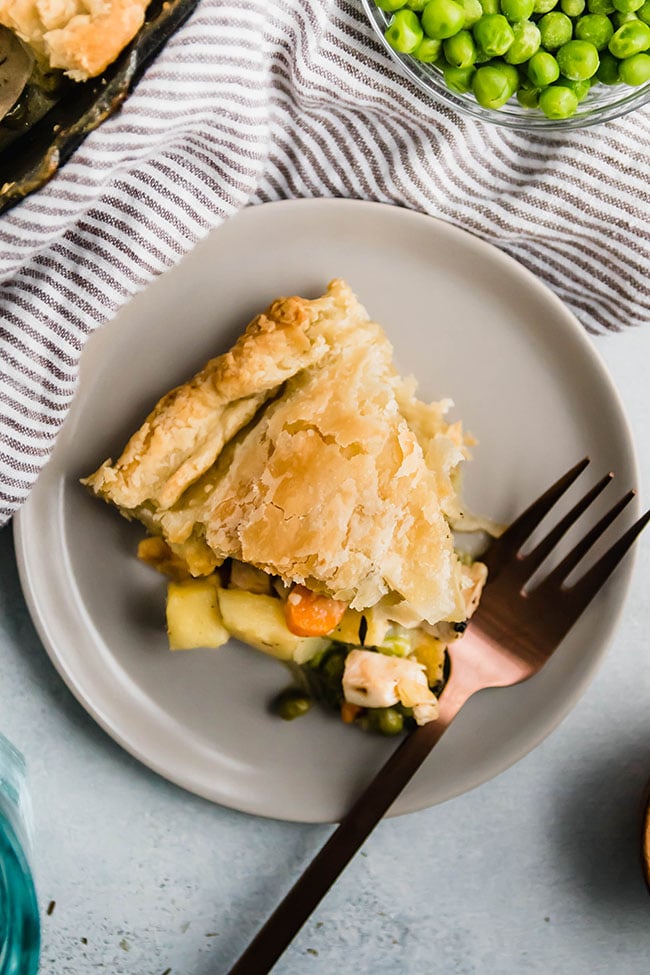 A slice of chicken pot pie on a grey plate with a copper fork.