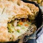 Chicken pot pie in a cast iron skillet with a silver serving spoon.