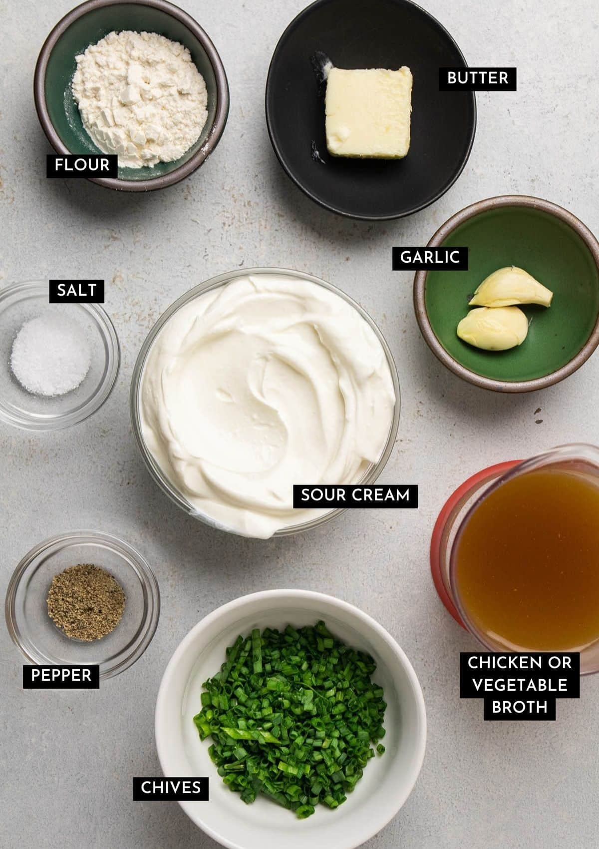 Sour cream sauce ingredients, organized into individual bowls on a white table.