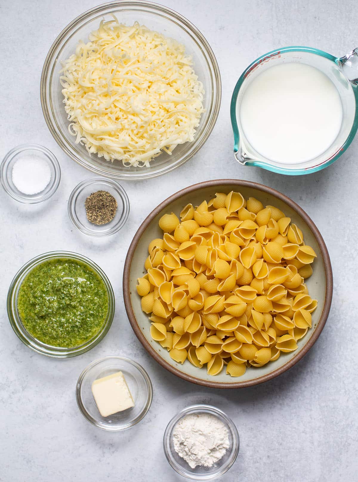 Mac and cheese ingredients, organized into individual bowls on a white table.
