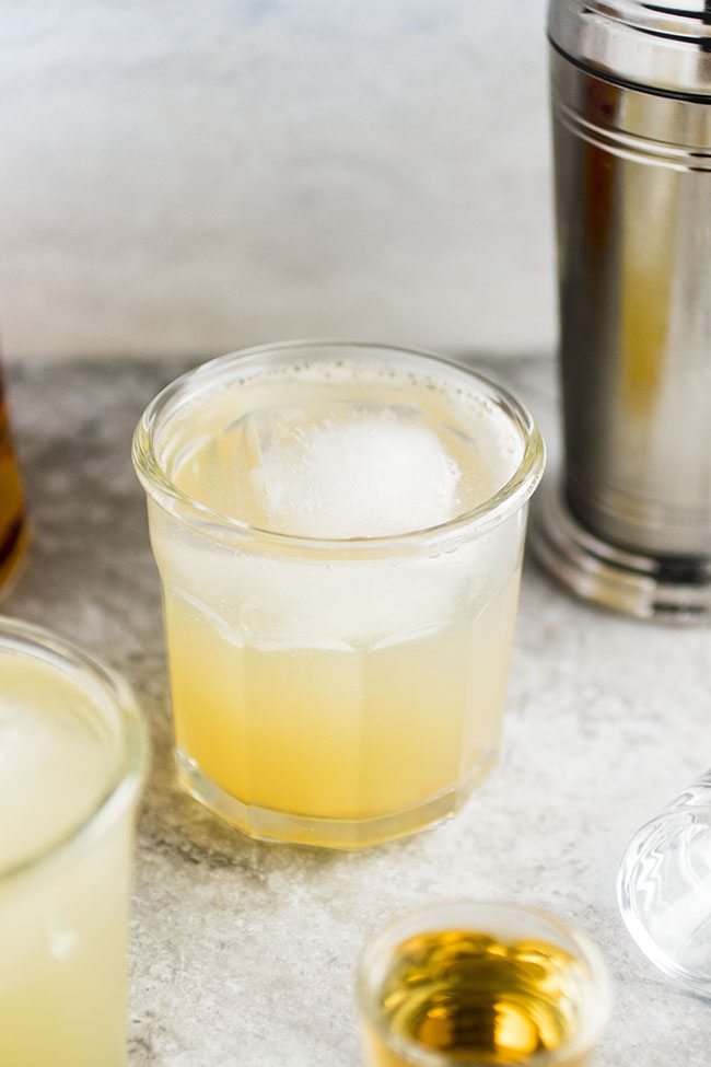 Whiskey lemonade in a short, thick glass with a large ice cube.