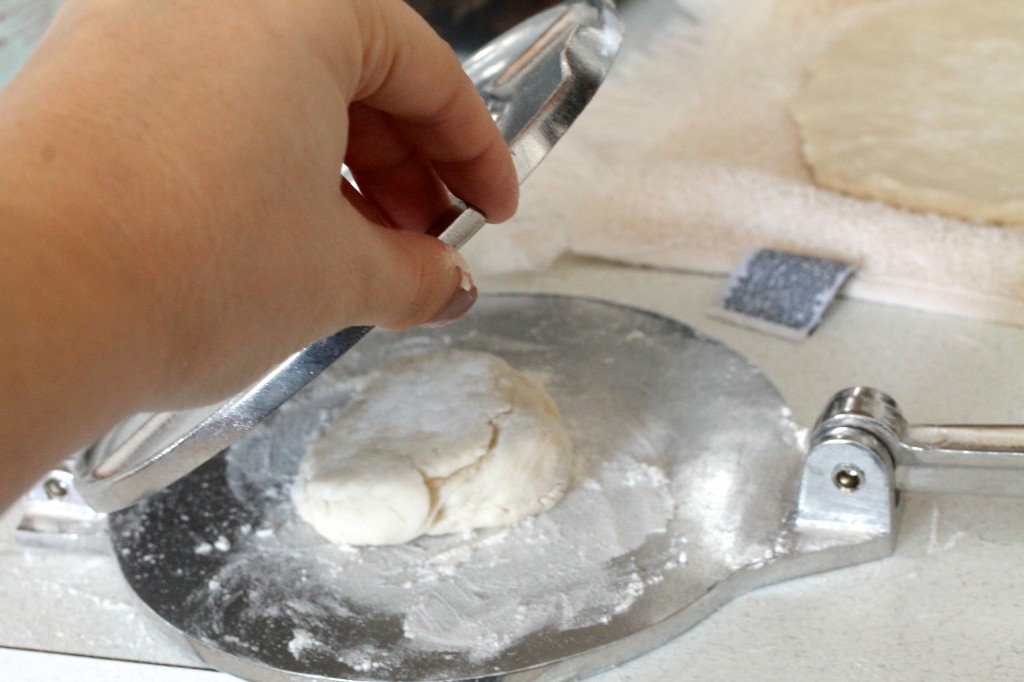 Closing a tortilla press with a small piece of dough inside.