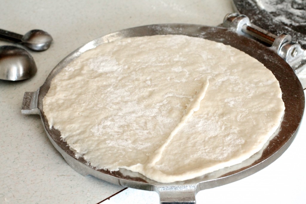 Tortilla dough rolled out on a tortilla press.