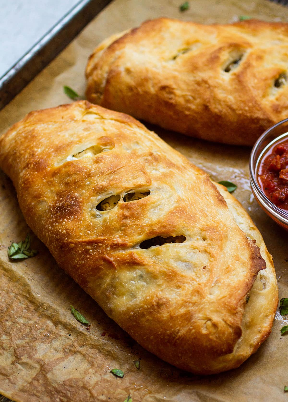 Baked calzone on a baking sheet lined with parchment paper.