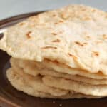 Stack of flour tortillas on a brown plate.