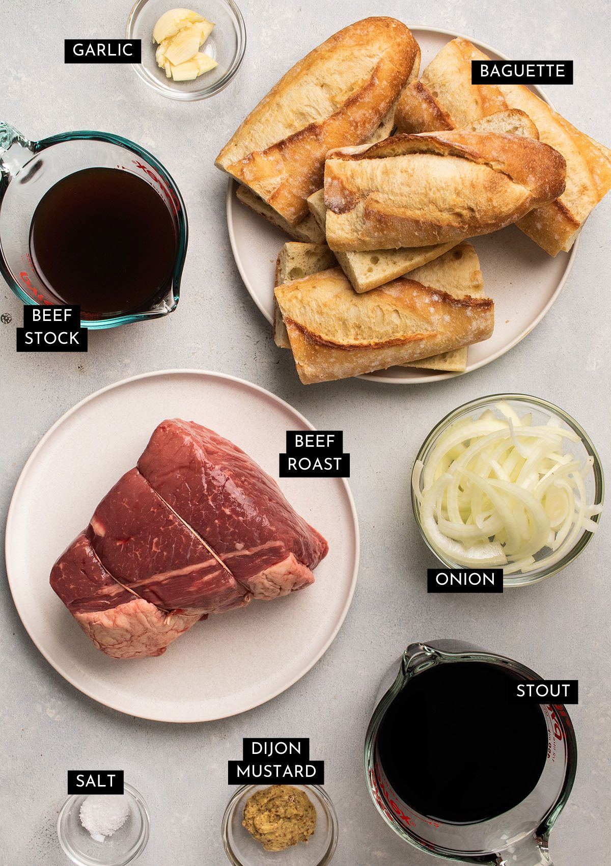 French dip ingredients, organized into individual bowls on a white table.