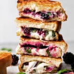 A stack of four blackberry grilled cheese sandwiches on a white table.
