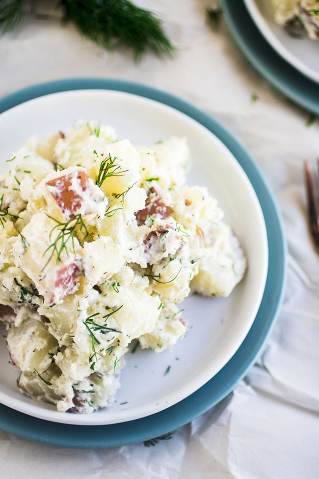 Potato salad on a blue and white plate, topped with fresh dill.