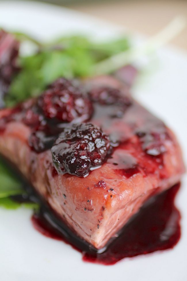 Close up of salmon with blackberry sauce drizzle on top.