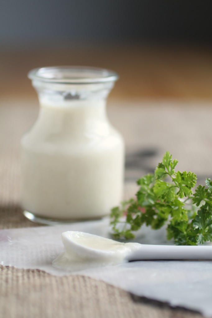 Jar of white sauce next to a bunch of fresh parsley.