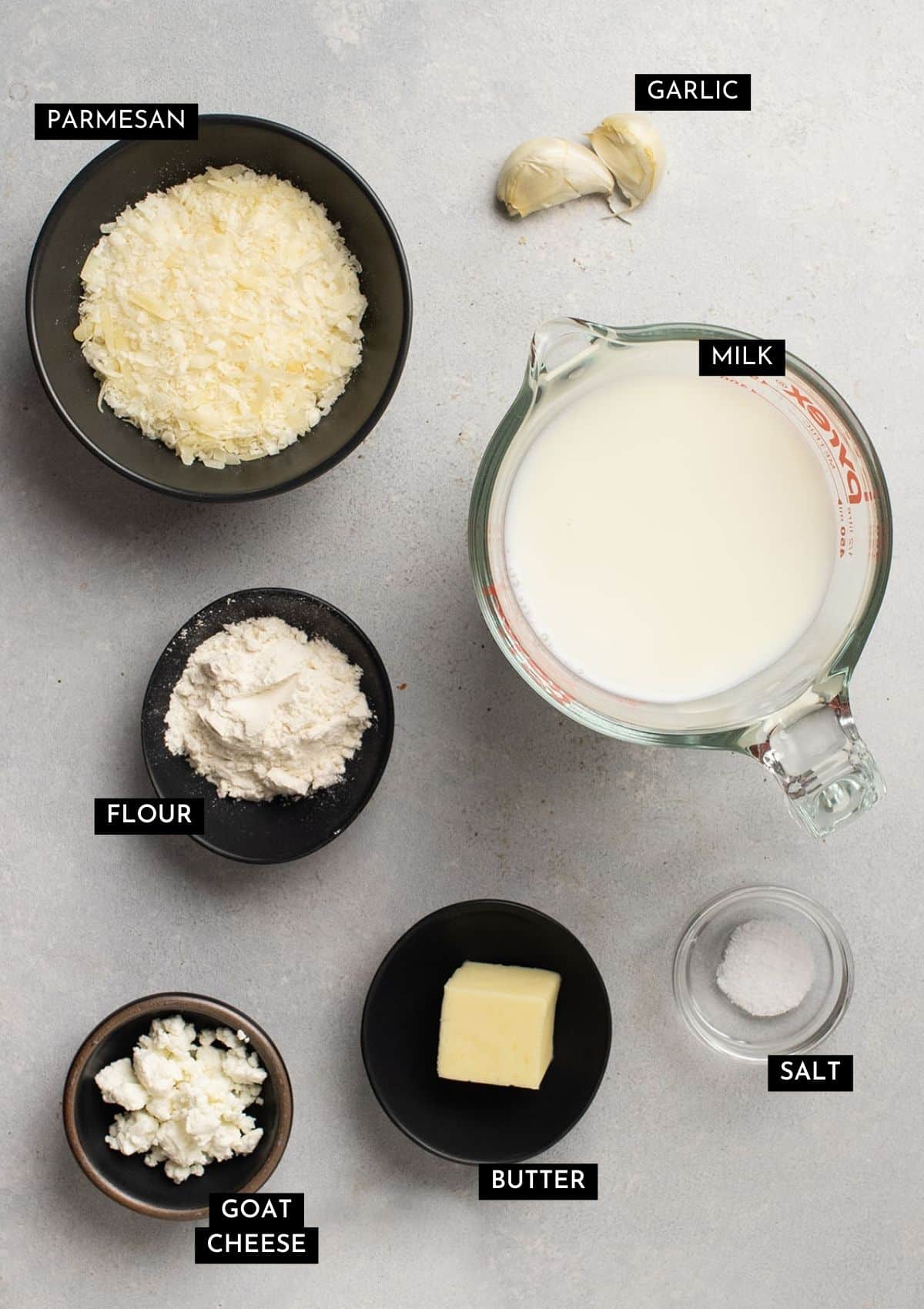 White sauce ingredients, organized into individual bowls on a white table.