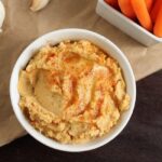 Bowl of roasted garlic hummus served with carrots