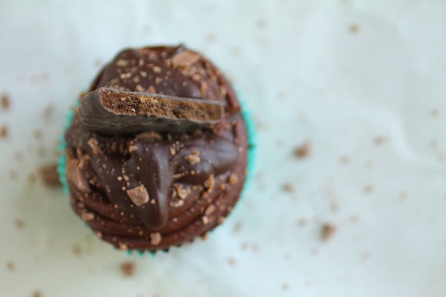 Aerial view of a chocolate cupcake topped with chocolate frosting and half of a cookie.