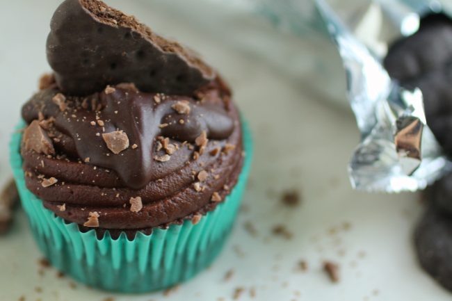 Chocolate cupcake next to a sleeve of thin mint cookies.