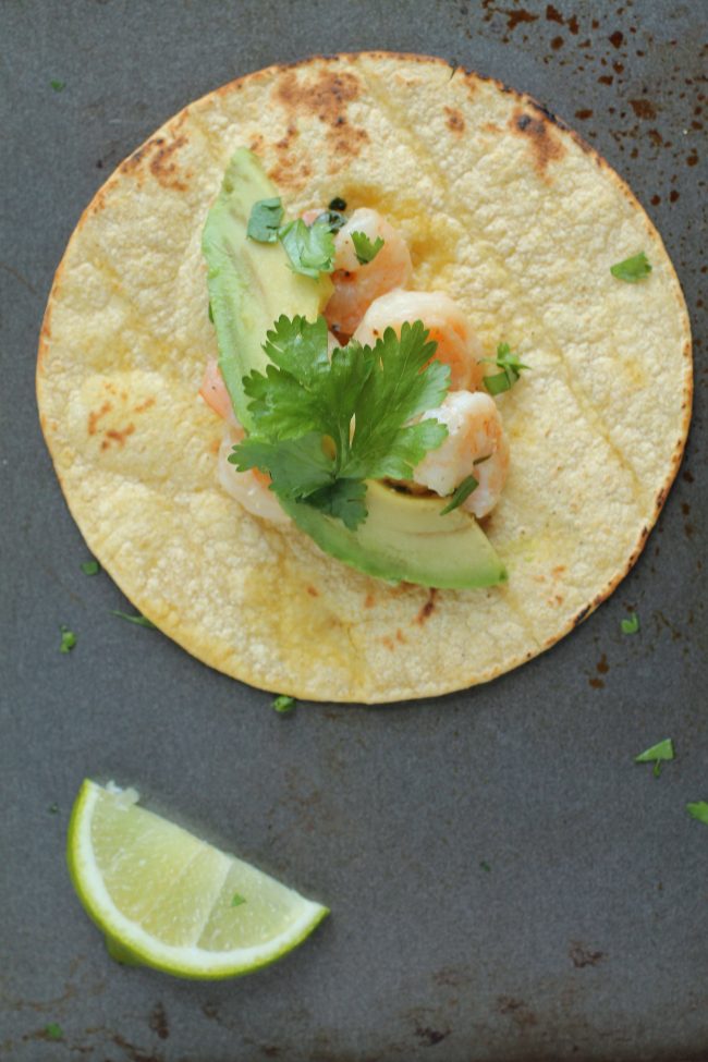 Aerial view of shrimp tacos on a dark surface.