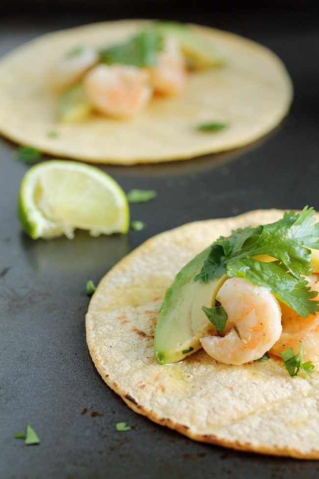 Lime wedges on a dark serving dish with shrimp tacos.