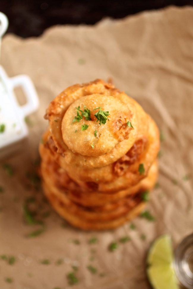 Aerial view of a stack of onion rings topped with fresh parsley.