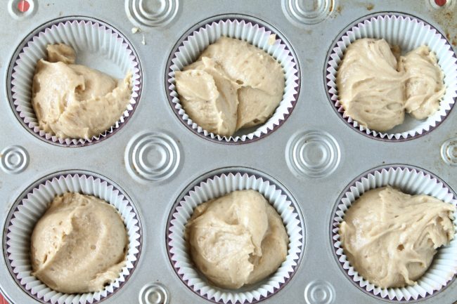 Cupcake batter in white liners in a cupcake pan.