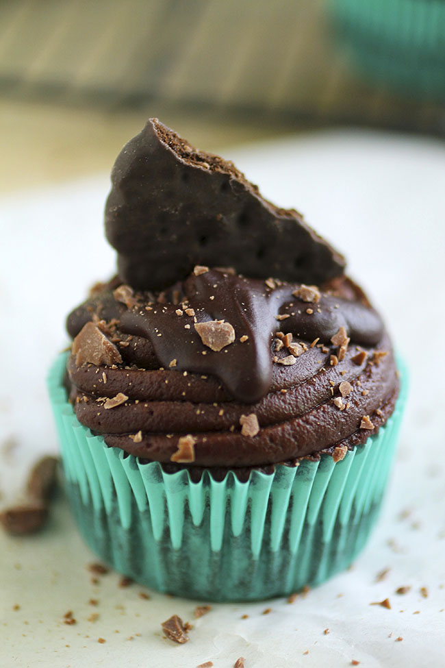 Chocolate cupcake topped with half a cookie and shaved chocolate.