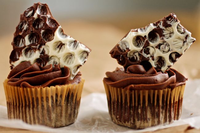 Two chocolate cupcakes, each topped with a piece of chocolate bark.