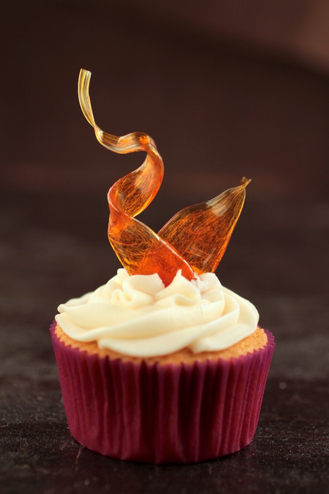 Vanilla cupcake topped with a sugar ribbon.