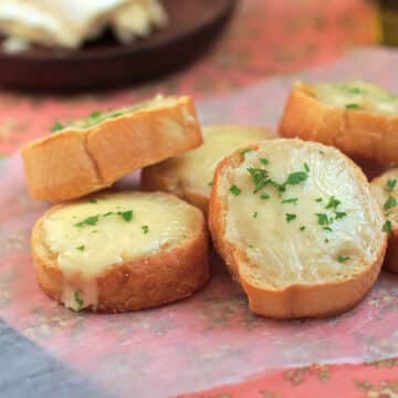 Crostini topped with melted brie next to a pink napkin.