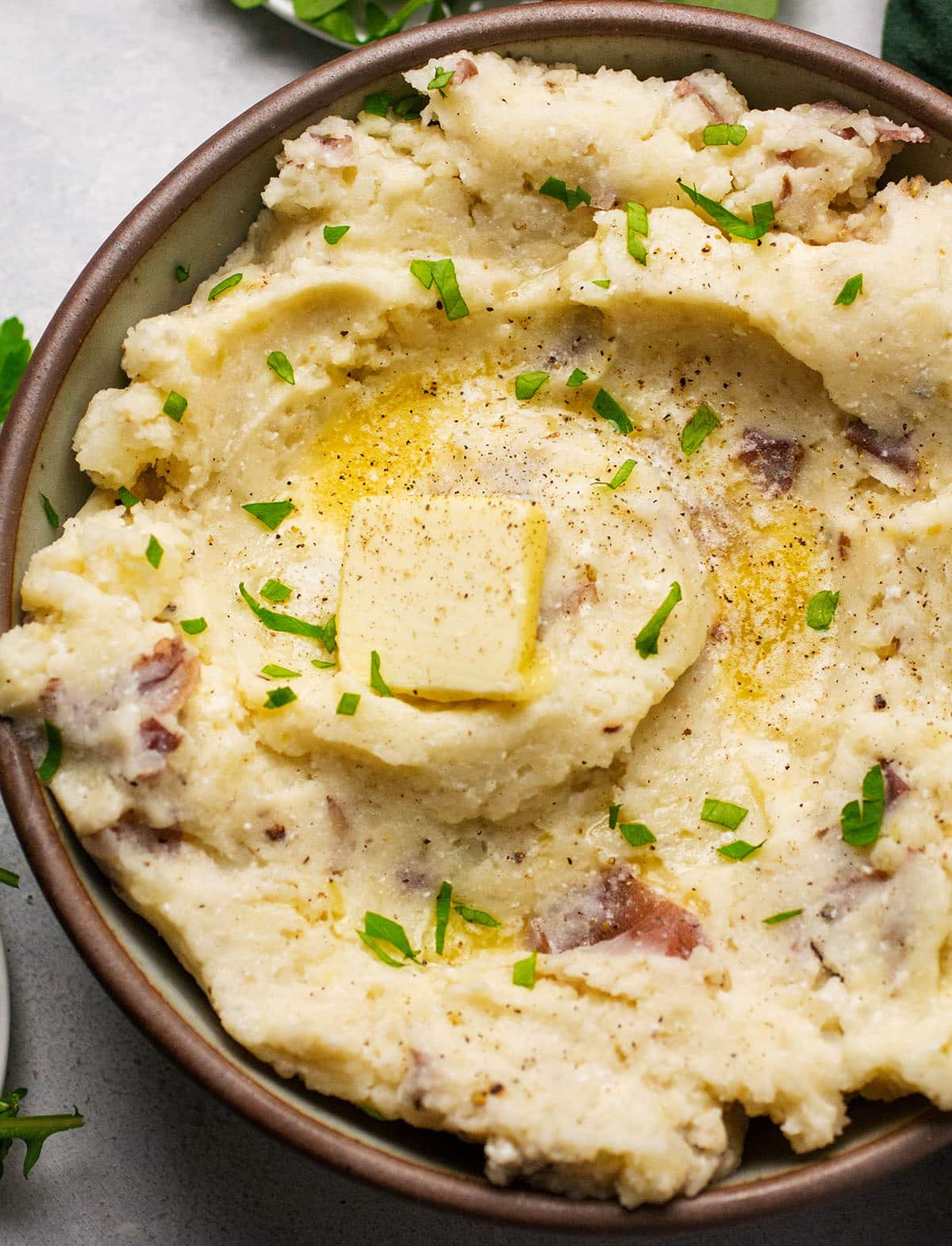 Mashed potatoes topped with fresh parsley and a pat of butter.