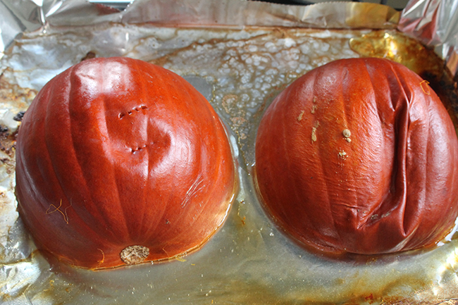 Two halves of a pumpkin, roasted and sitting on a baking sheet.