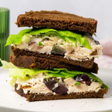 Two halves of a chicken salad sandwich, stacked on a white plate.