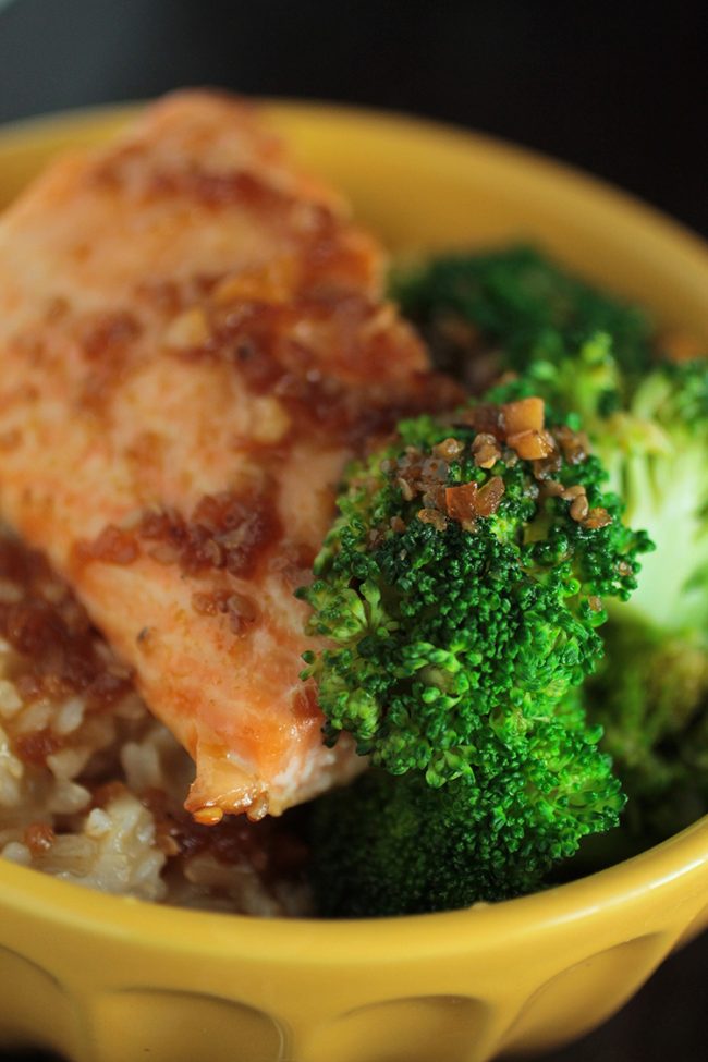 Close up of steamed broccoli next to a piece of teriyaki salmon.