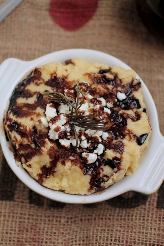 White dish filled with mashed potatoes and topped with goat cheese and balsamic drizzle.