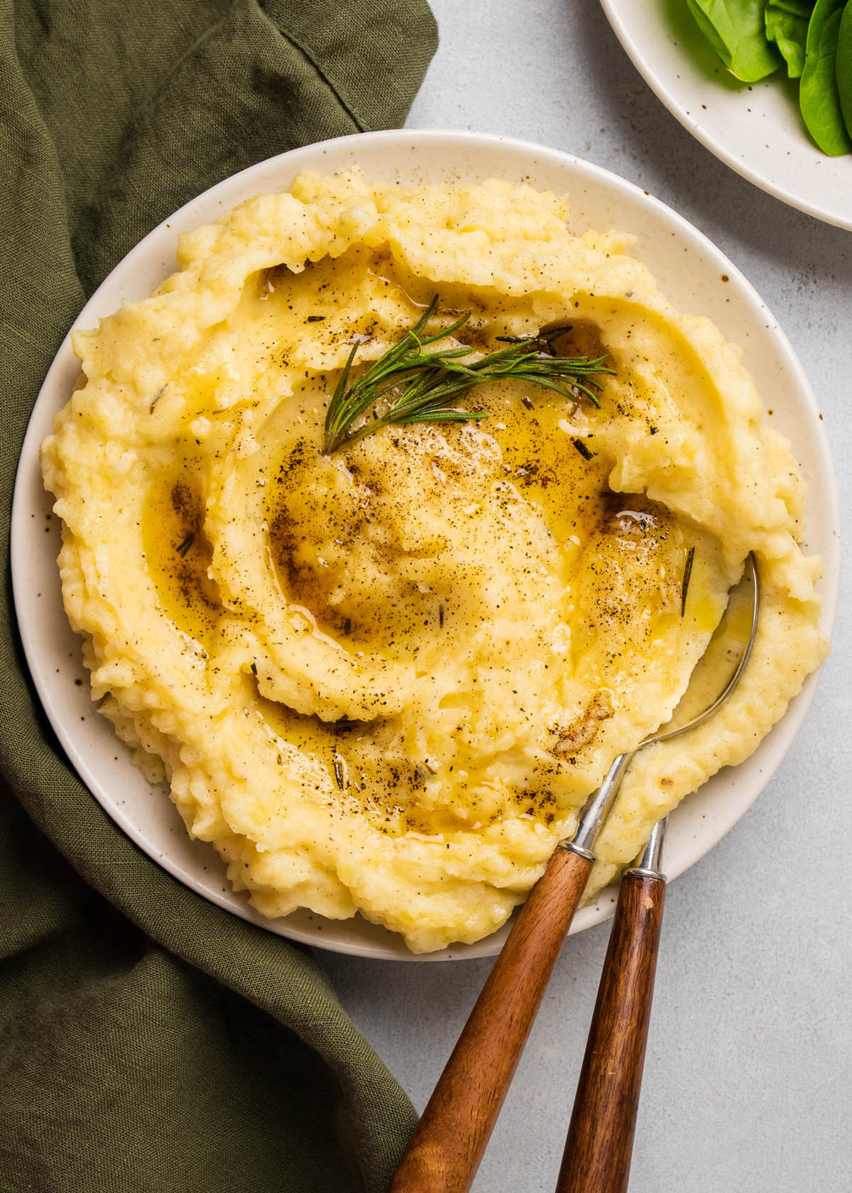 Mashed potatoes topped with browned butter and a fresh rosemary sprig.